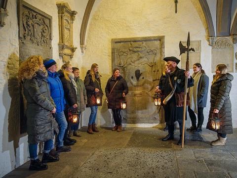 Eine Gruppe von 10 Personen bei einer Nachtwächterführung im Kreuzgang.