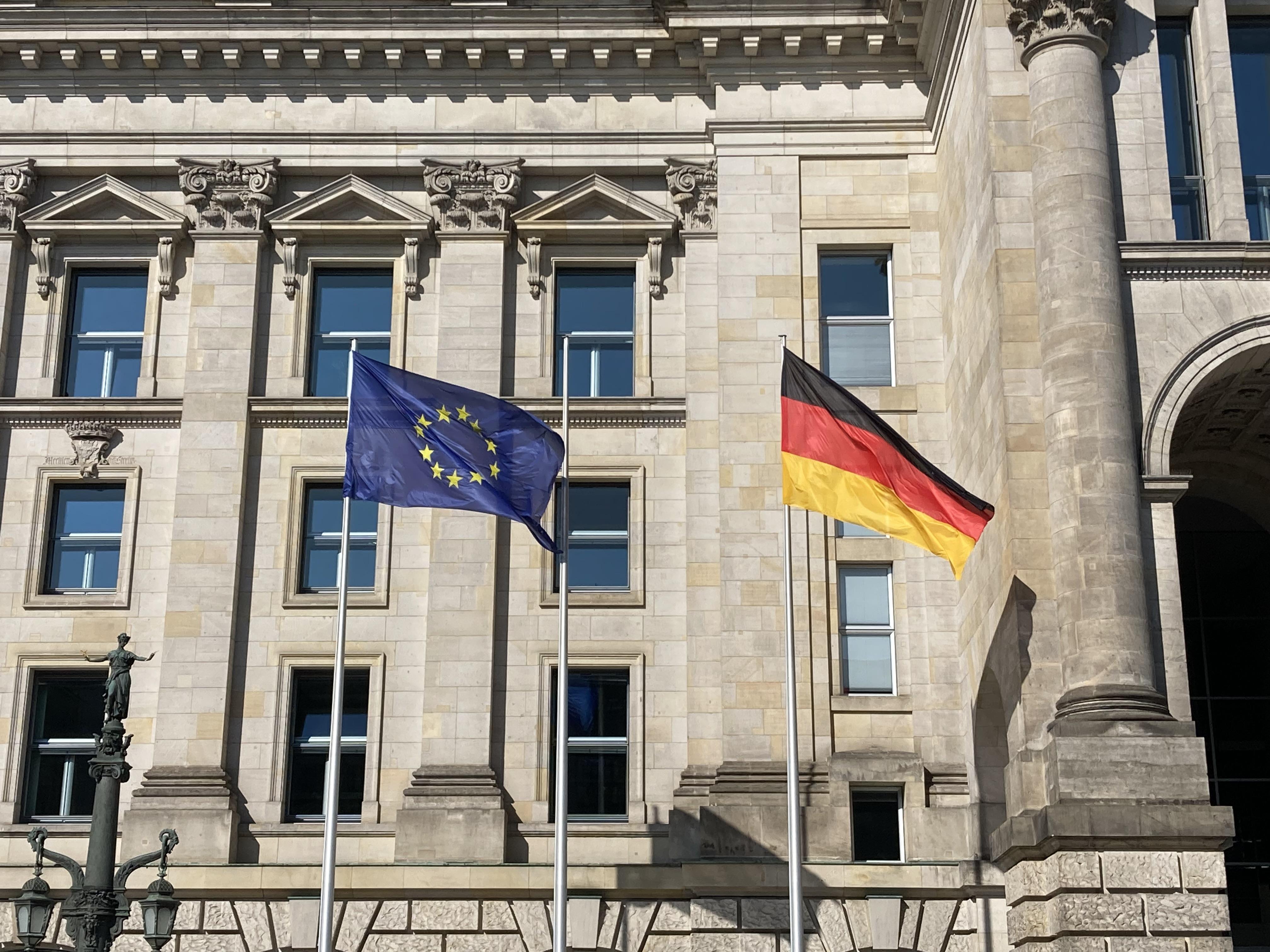 Zwei Flaggen wehen vom deutschen Reichstag. Links eine Europa-Flagge, rechts eine Deutschland-Flagge