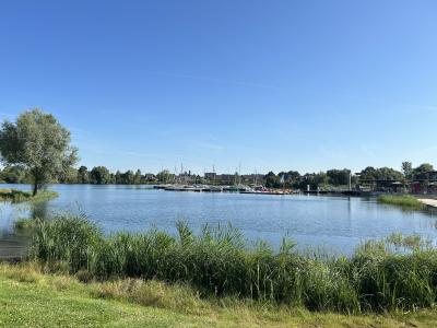 Die Südsee Xanten bei strahlendem Sonnenschein im Sommer. Rechts ist das Gebäude der Gastronomie zu sehen, links der Anlegesteg mit verschiedenen Booten.