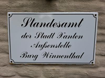 Ein Weißes Hinweisschild mit der Aufschrift "Standesamt der Stadt Xanten Außenstelle Burg Winnenthal"
