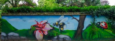 Mauer die mit Graffiti bemalt ist, es ist eine Blume eine Biene und ein Marienkäfer auf dem Bild zu sehen.