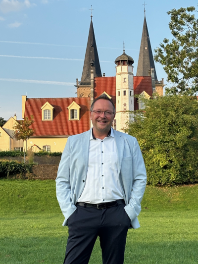 Bürgermeister Thomas Görtz steht im Kurpark. Im Hintergrund sind die Spitzen des Doms zu sehen.