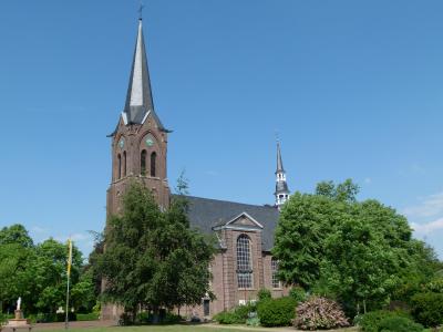 Außenansicht auf die Kirche in Marienbaum. Davor sind einige Laubbäume
