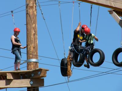 Ausschnitt des Kletterparks in Xanten. Ein Kind und ein Mann klettern über Autoreifen. ein Mädchen wartet links auf der Plattform