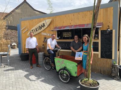 Bürgermeister Thomas Görtz sitzt auf einem Lastenrad, welches vor der Tikibar steht.