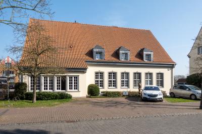 Haus der Begegnung von vorne. Ein Haus mit rotem Dach und gelber Fassade.