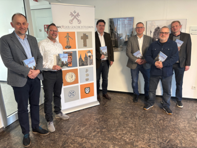 6 Menschen stehen bei einem Aufsteller, jeder hat ein Buch in der Hand
